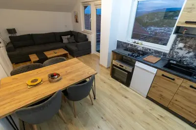 a kitchen and living room with a table and a couch at Guest House Lejla 2 in Travnik