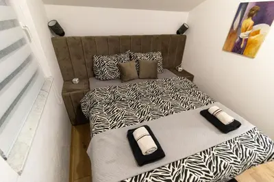 a small bedroom with a bed with zebra print sheets at Guest House Lejla 2 in Travnik