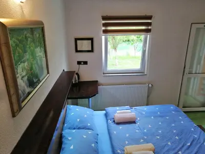 a bedroom with a blue bed and a window at Domaćinstvo Una-Ostrovica in Kulen Vakuf
