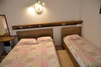 a bedroom with two beds and a clock on the wall at Domaćinstvo Una-Ostrovica in Kulen Vakuf