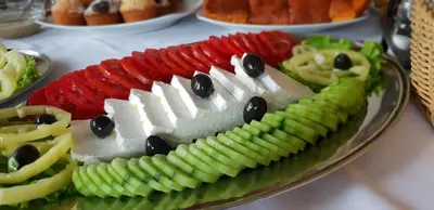 a plate of food on a table with fruit and vegetables at HOTEL Pyramid Lodge in Visoko