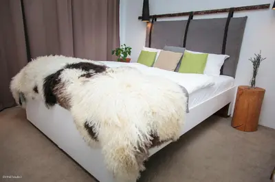 a bedroom with a white bed with a fuzzy blanket at HOTEL Pyramid Lodge in Visoko