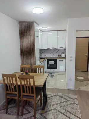 a dining room with a table and chairs and a kitchen at Apartman L&S in Doboj