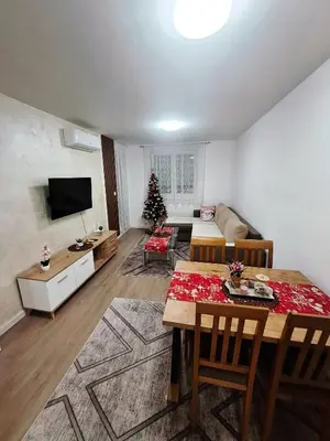 a living room with a table and a christmas tree at Apartman L&S in Doboj