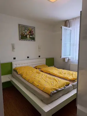 two beds in a bedroom with yellow sheets and a window at Villa Sienna in Smrdan