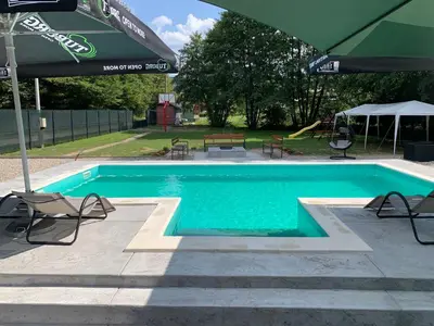 a swimming pool with chairs and an umbrella at Vikendica Sofijina Luka in Slatina Varoš