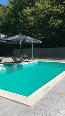 a swimming pool with an umbrella and a table and chairs at Vikendica Sofijina Luka in Slatina Varoš