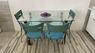 a glass table with four chairs and a purple hat on it at Apartman Dina in Sanski most