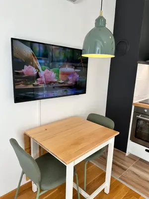 a dining room table with chairs and a tv on the wall at Studio Mint&White Borik in Banja Luka