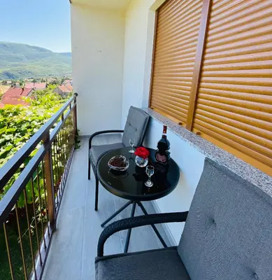 a table with a bottle of wine on a balcony at Apartman Lucija in Rumboci