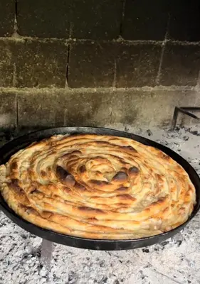 a pie is being cooked in a pan in an oven at Apartman Lucija in Rumboci