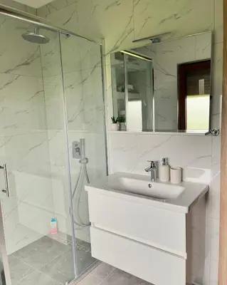 a white bathroom with a sink and a shower at Apartman Lucija in Rumboci