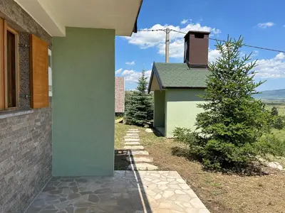 a side view of a house with a green at Vikendica Mati in Kupres