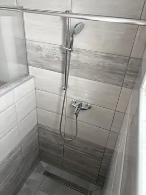 a shower with a glass door and a shower head at Apartman Jasmina in Pokoj