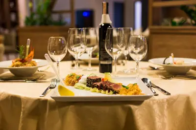 a plate of food on a table with wine glasses at Hotel Jelena in Banja Luka