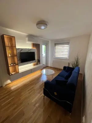 a living room with a blue couch and a flat screen tv at Elita Apartmani in Ivišovo Greblje