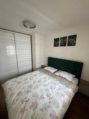 a bedroom with a bed with a green headboard at Elita Apartmani in Ivišovo Greblje