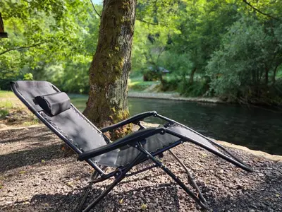 a black folding chair sitting next to a river at Villa Tea in Šipovo