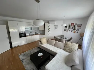 a living room with a white couch and a table at Apartman Pannonica Centar in Tuzla