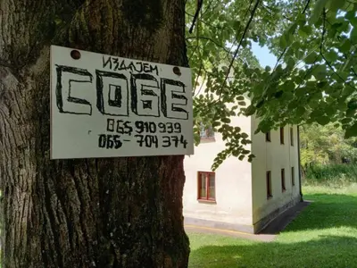 a sign hanging on a tree in front of a building at Kuća Knežević in Mlječanica