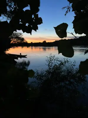 a person in a boat on a lake at sunset at Apartmani Una Lux2 in Spilja