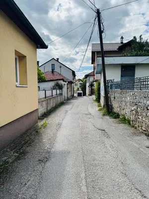 an empty road in a village with houses and a wall at San Travnik in Travnik