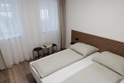 a bedroom with a white bed and two stools at San Travnik in Travnik