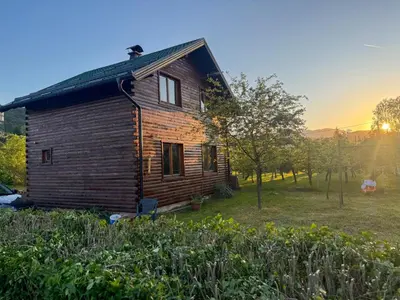 an old wooden house in a field with the sunset at Guest House Seka in Bihać
