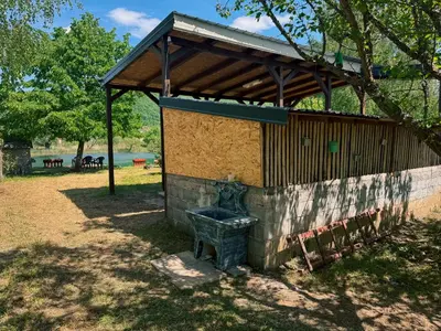 a wooden building with a bench in a park at Guest House Seka in Bihać