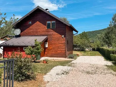 a log home with a red house at Guest House Seka in Bihać
