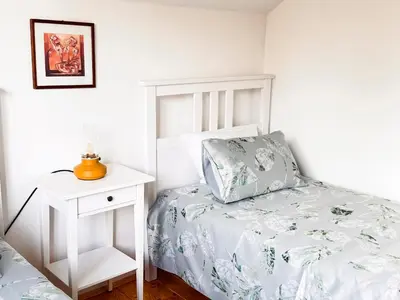a white bedroom with a bed and a night stand at Guest House Seka in Bihać