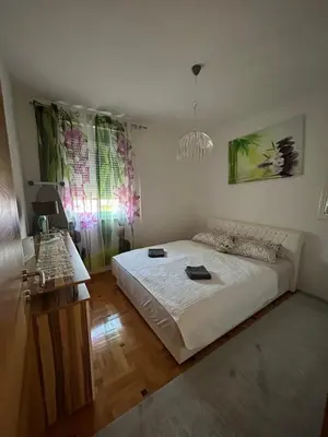 a bedroom with a large bed and a chandelier at Apartman Murtić in Bihać
