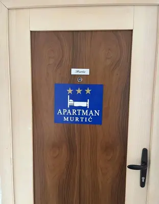 a sign on a door with the name of an arwegian military at Apartman Murtić in Bihać
