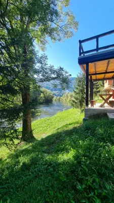 a building with a tree next to a river at Bad and Breakfast Majestik in Gornji Ribnik