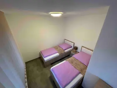 two beds in a small room with purple sheets at Arena 2 in Ripač