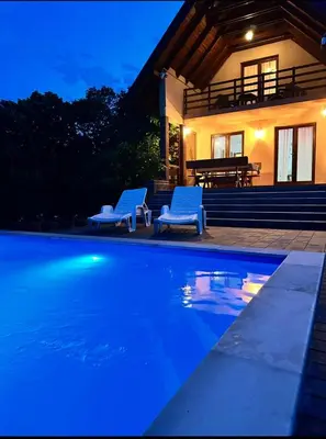 a swimming pool with two blue chairs and a house at Foresta Home in Gradačac