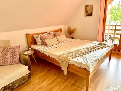 a bedroom with a large bed and a chair at Foresta Home in Gradačac