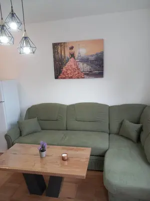 a living room with a green couch and a wooden coffee table at Apartman LAVANDA in Teslić