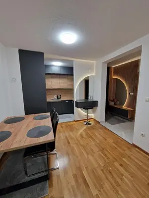 a living room with a table and a kitchen at Apartman 3 Tuzla in Tuzla