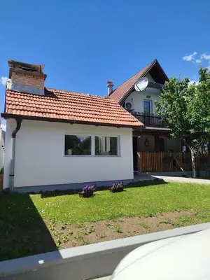 a white house with a clock on the roof at Kuća za odmor Noah in Bihać
