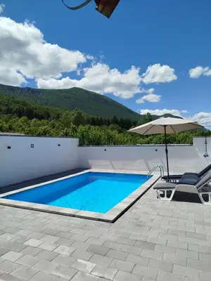 a swimming pool with an umbrella and a table and chairs at Kuća za odmor Noah in Bihać