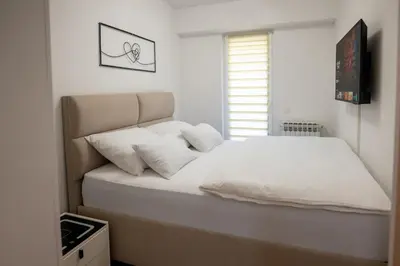 a bedroom with a bed with white sheets and pillows at Aurum apartman Žepče in Žepče