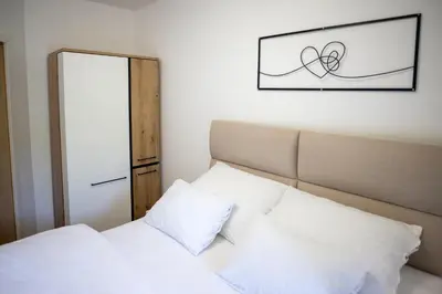 a bedroom with a bed with white sheets and a mirror at Aurum apartman Žepče in Žepče