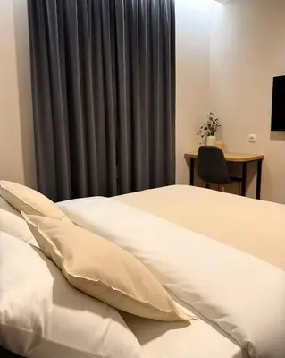 a bedroom with two beds and a gray curtain at Stari Hrast Apartmani in Bosanska Gradiška
