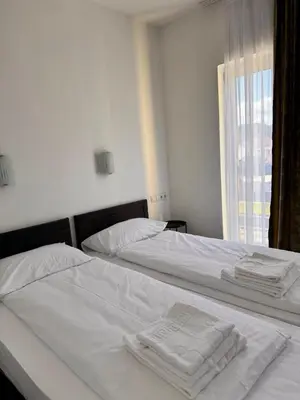 two beds in a bedroom with white sheets and towels at Prenoćište Stanica in Bosanska Krupa