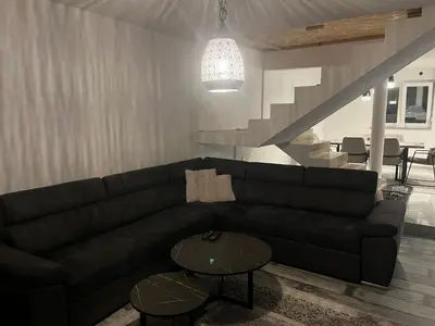 a living room with a black couch and a table at Peace Holiday Home in Bihać