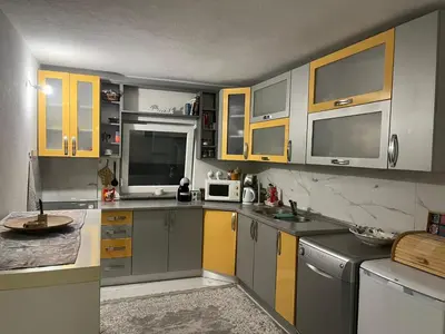 a kitchen with gray and yellow cabinets and appliances at Peace Holiday Home in Bihać