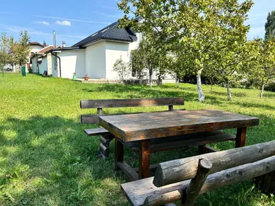 two wooden benches and a picnic table in a field at Peace Holiday Home in Bihać