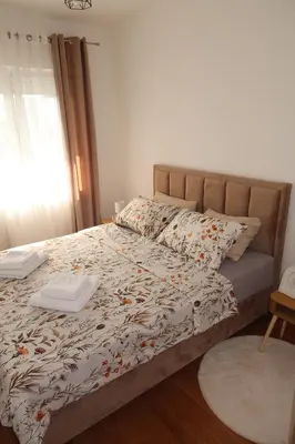 a bedroom with a bed with a comforter on it at Lumière Apartment in Banja Luka