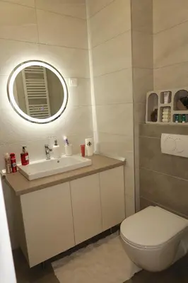 a bathroom with a sink and a toilet and a mirror at Lumière Apartment in Banja Luka